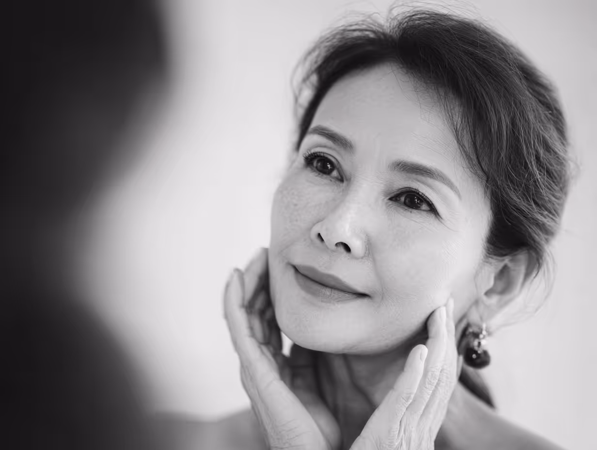 Close-up of a middle-aged woman gently touching her face with a serene expression.