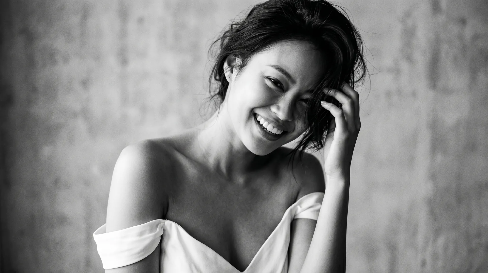 Black-and-white portrait of a bride laughing freely, head tilted, hand in her hair