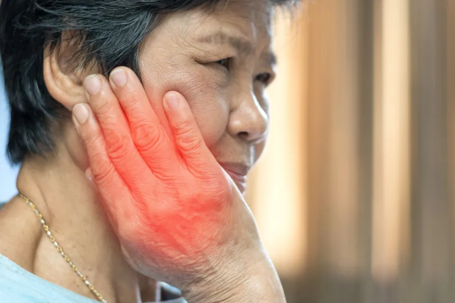 elderly women hand on cheek showing signs of jaw pain tmj