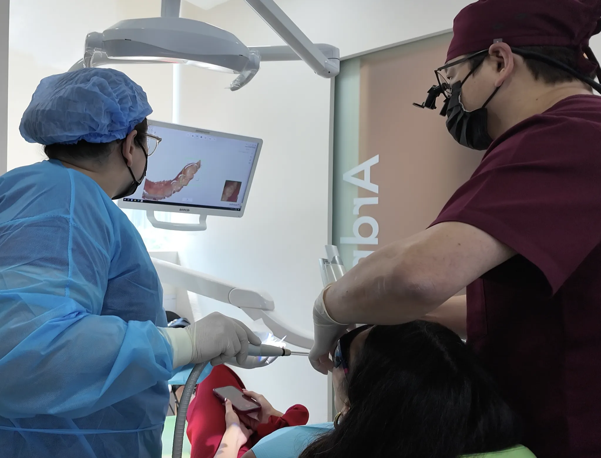 Dr. Jerry Lim and his assistant using iTero 3D Scanning technology to examine a patient's teeth in a dental clinic.
